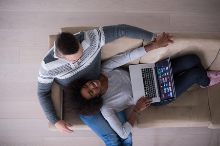 Young multiethnic couple relaxes in the luxury living room, using a laptop computer top viewの写真素材