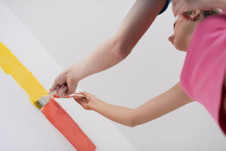 happy smiling young couple painting interior wall of new houseの写真素材