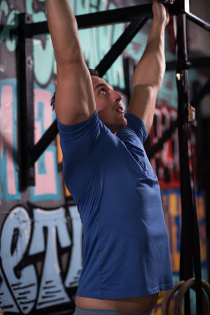 strong young man doing pull ups on a bar in a gym