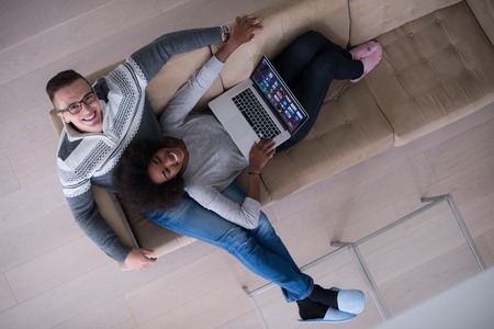 Young multiethnic couple relaxes in the luxury living room, using a laptop computer top viewの写真素材