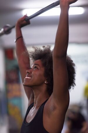 Young Cute african american sport woman in fitness room lifting empty barの写真素材