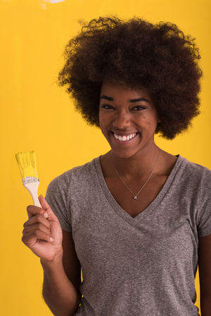 portrait of a young beautiful African American woman painting wall in her new apartmentの写真素材