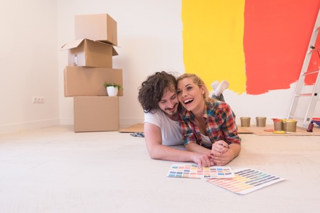 Happy young couple relaxing after painting a room in their new house on the floorの写真素材