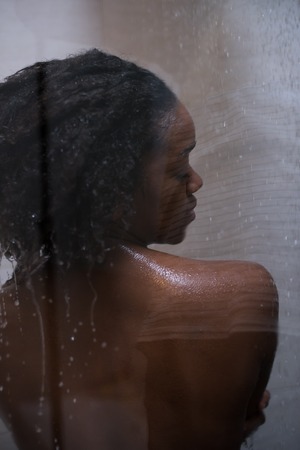 Woman in the shower,beautiful black young female showering under refreshing water, healthy lifestyle, enjoying time in luxury spa resortの写真素材