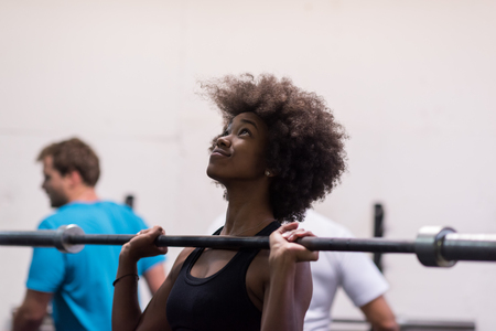Young Cute african american sport woman in fitness room lifting empty barの写真素材