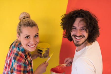 happy smiling young couple painting interior wall of new houseの写真素材