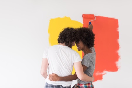 happy young multiethnic couple painting interior wall of new houseの写真素材
