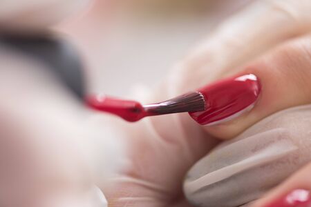 Woman hands receiving a manicure in beauty salon. Nail filing. Close up, selective focus.の写真素材