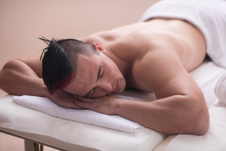 attractive handsome man resting in a spa massage center, lying on table relaxing closed eyes  concept of men beauty health careの写真素材