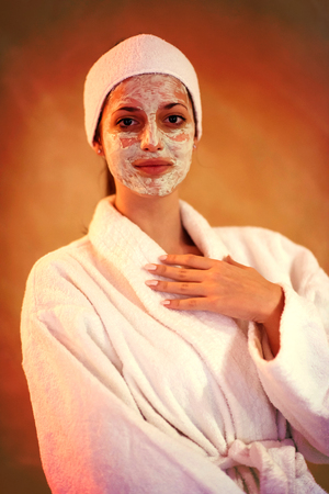 Spa Woman applying Facial Mask  Beauty Treatments  Close up portrait of beautiful girl with a towel on her head applying facial maskの写真素材