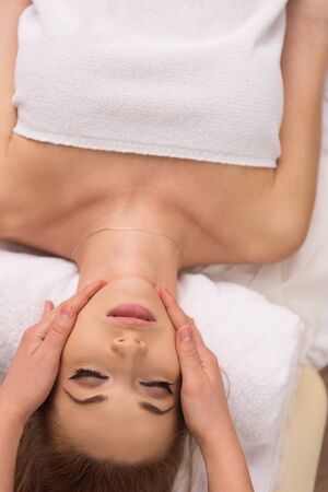 Young beautiful relaxed woman receiving a head massage in a spa centreの写真素材