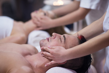 happy young beautiful couple enjoying head massage at the spa