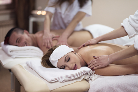 Relaxed young beautiful couple receiving a back massage from masseur in a spaの写真素材