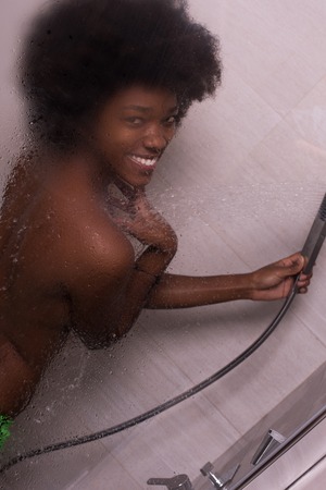 Woman in the shower,beautiful black young female showering under refreshing water, healthy lifestyle, enjoying time in luxury spa resortの写真素材