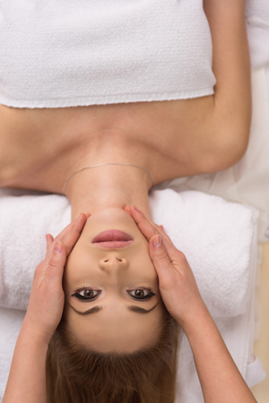Young beautiful relaxed woman receiving a head massage in a spa centreの写真素材
