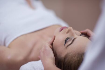 Young beautiful relaxed woman receiving a head massage in a spa centreの写真素材