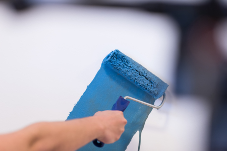 Decorator's hand painting wall with rollerの写真素材