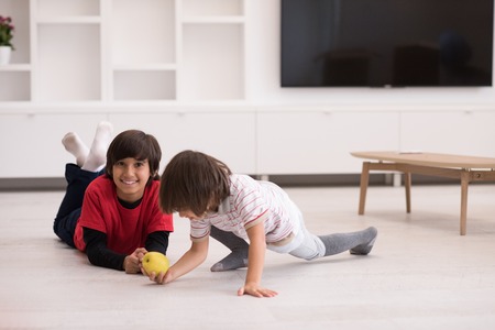 happy young boys having fun with an apple on the floor in a new modern homeの写真素材