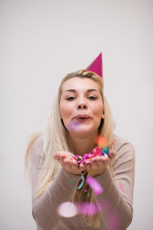 beautiful young woman celebrating new year and chrismas party while blowing confetti decorations to...