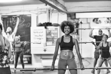 Young Cute african american sport woman in fitness room lifting empty barの写真素材