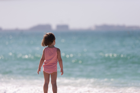 happy little girl at the seaside in the summer.Adorable little girl at beach during summer vacation. Happy baby by the sea or oceanの写真素材
