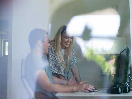 young man and woman operators of security systems looking at CCTV footage at desk in officeの写真素材