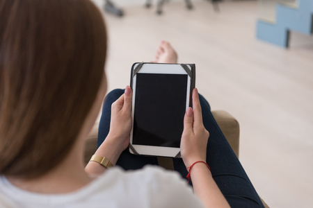 young happy woman sitting on sofa with tablet computer at luxury homeの写真素材