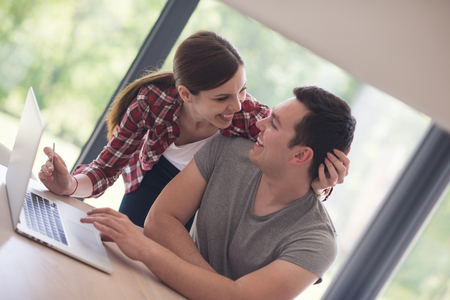 happy young couple buying online using laptop a computer and a credit card in their luxury home villaの写真素材