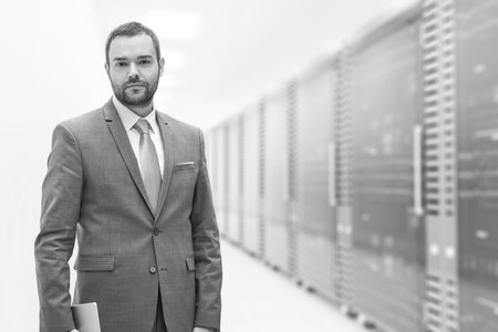 Portrait of young businessman in server room using tablet