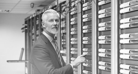Portrait of senior businessman working in big rack server room