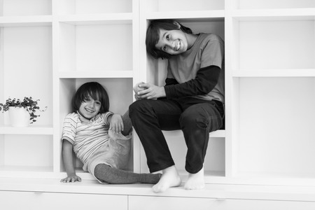happy young boys are having fun while posing on a shelf in a new modern homeの写真素材