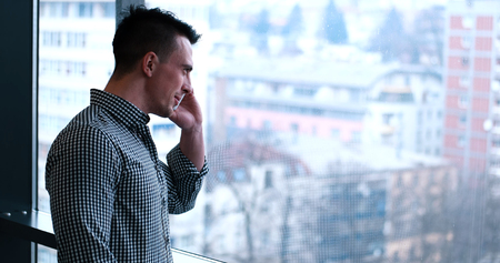 laughing man talking on the phone in office interiorの写真素材