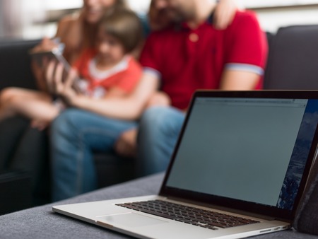 Happy Young Family Playing Together with tablet at home sitting on the sofaの写真素材