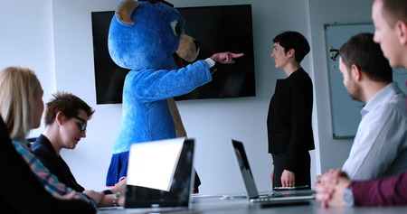 Boss dresed as teddy bear having fun with bussines people in modern corporate officeの写真素材