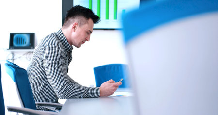 relaxed young businessman using smart phone at modern startup business office