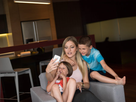 Happy family siting on sofa and using cell phone for video call  at homeの写真素材