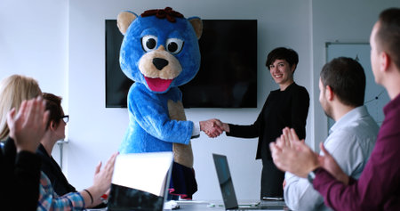 Boss dresed as teddy bear having fun with bussines people in modern corporate officeの写真素材