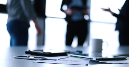 Devices on table with business people in background in modern office buildingの写真素材
