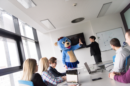 Boss dresed as teddy bear having fun with bussines people in modern corporate officeの写真素材