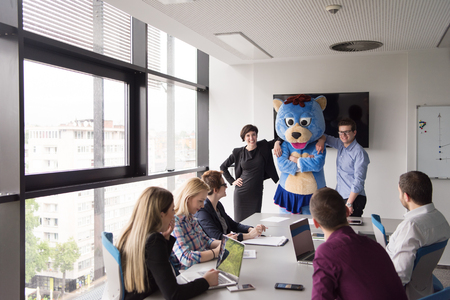 Boss dresed as teddy bear having fun with bussines people in modern corporate officeの写真素材