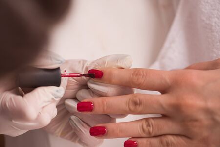 Woman hands receiving a manicure in beauty salon. Nail filing. Close up, selective focus.の写真素材