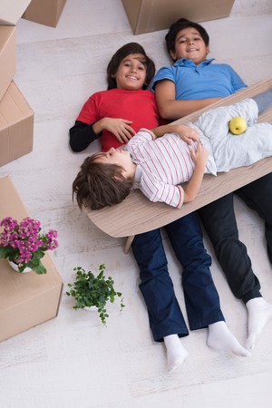 portrait of happy young boys with cardboard boxes around them in a new modern home top viewの写真素材