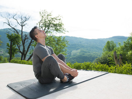 young handsome man doing morning yoga exercises in front of his luxury home villa