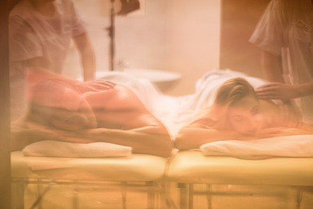 Relaxed young beautiful couple receiving a back massage from masseur in a spaの写真素材