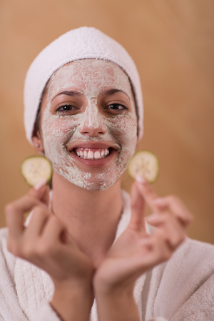 Spa Woman applying Facial Mask  Beauty Treatments  Close up portrait of beautiful girl with a towel on her head applying facial maskの写真素材