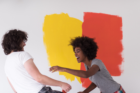 happy young multiethnic couple painting interior wall of new houseの写真素材