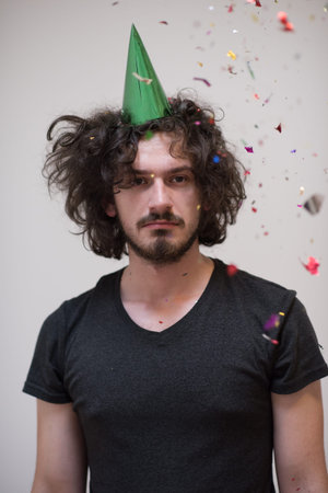 young man celebrating new year and chrismas party while blowing confetti decorations to cameraの写真素材