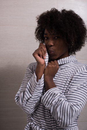 Portrait of young beautiful black woman wearing  bathrobe standing in the bathroomの写真素材