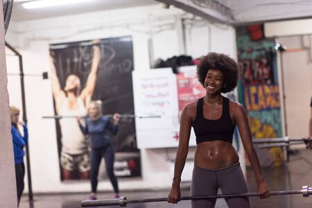 Young Cute african american sport woman in fitness room lifting empty barの写真素材