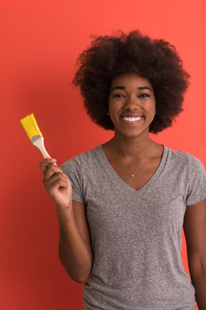 portrait of a young beautiful African American woman painting wall in her new apartmentの写真素材